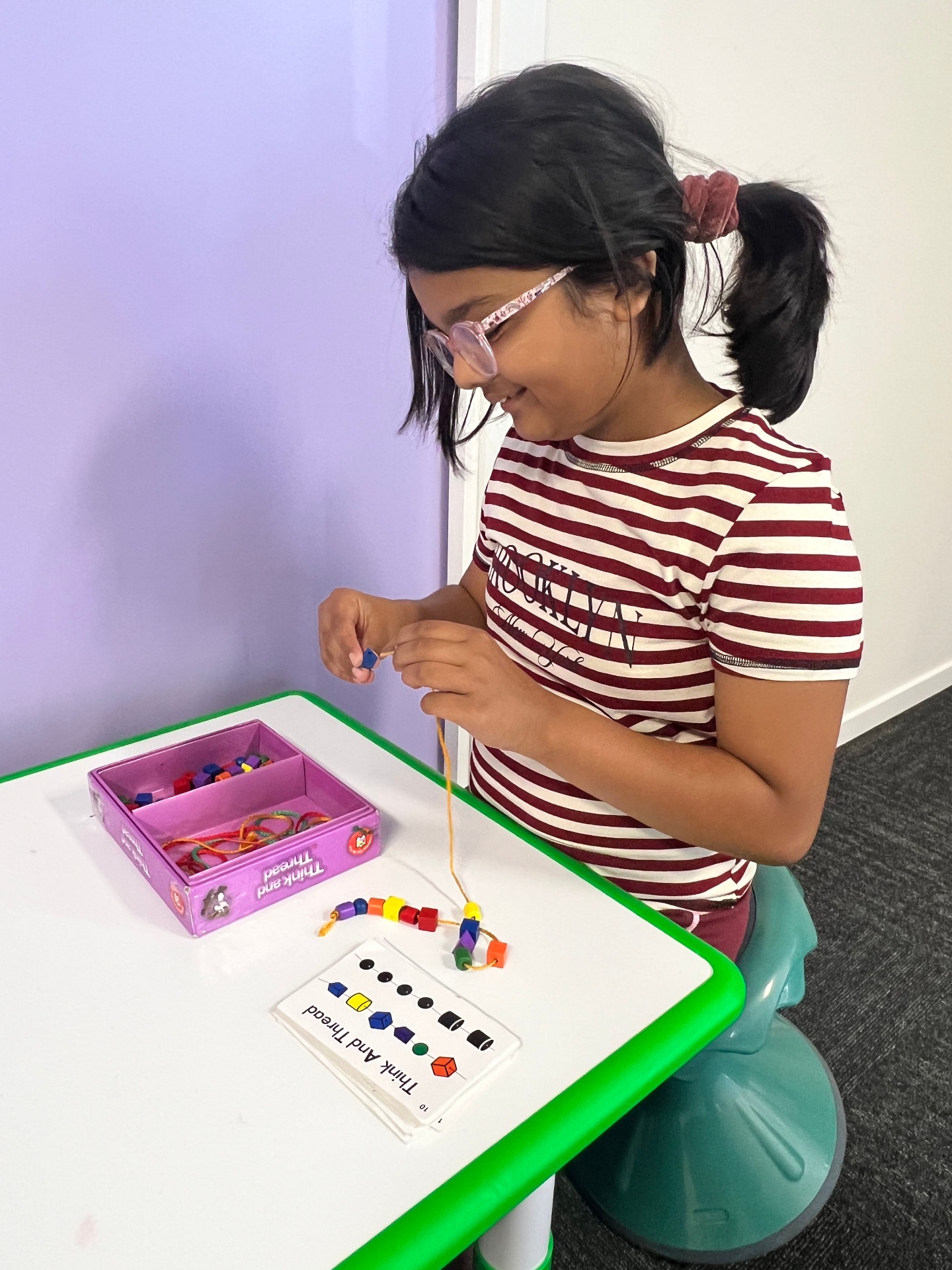 Child smiling while threading beads