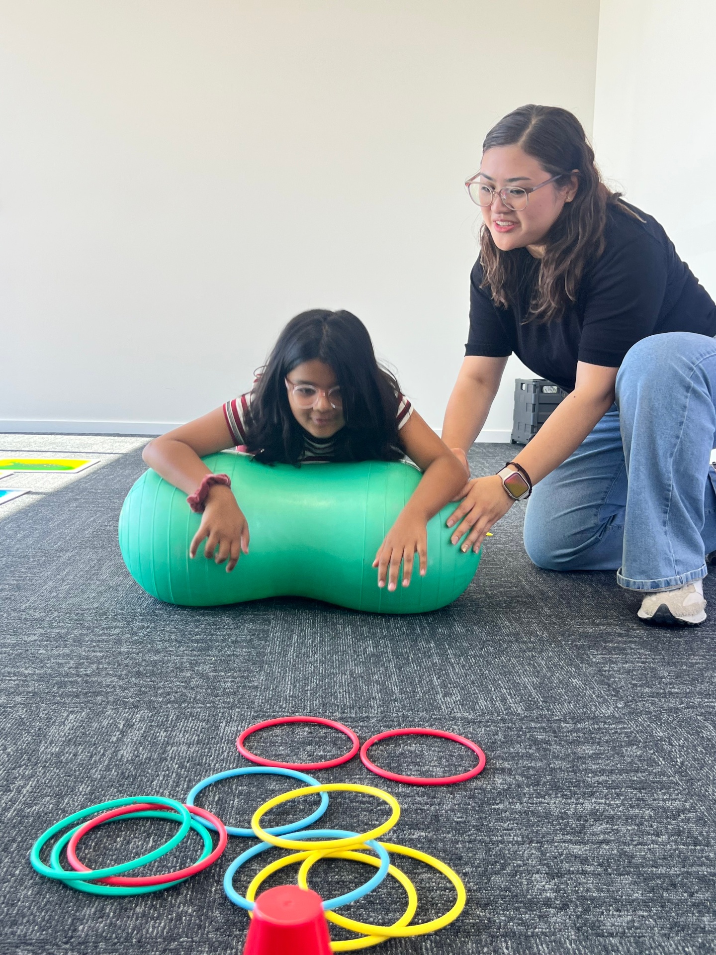 Child working on core strength with peanut ball and rings